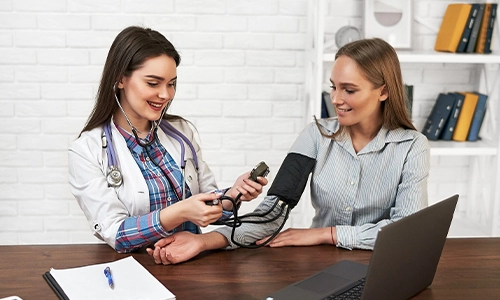 A family doctor measuring a woman's blood pressure with a tonometer during an annual health exam
