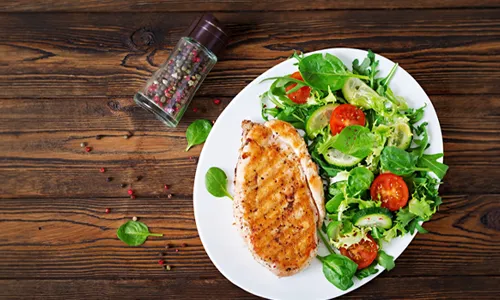 Top view of Grilled chicken breast and fresh vegetable salad