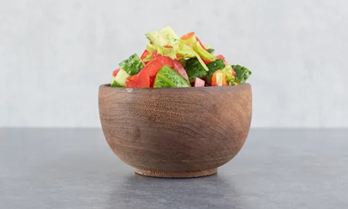Sliced fruits, vegetables and seeds in wooden bowl
