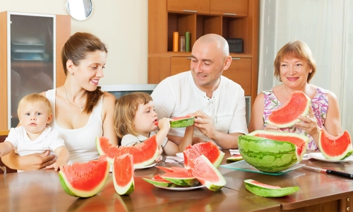 Multi-generational family enjoying fresh watermelon together at the dining table