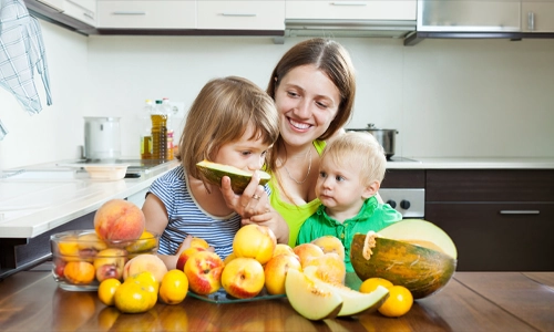 Mother with daughters over fresh fruits on the table