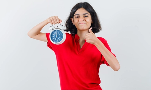 A girl holding a clock representing daylight saving time