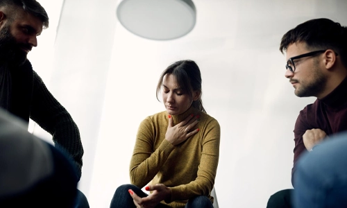 Depressed woman sharing her problems with members of group therapy