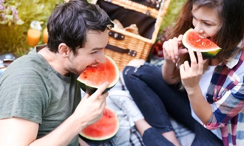 Couple enjoying watermelon during an outdoor picnic