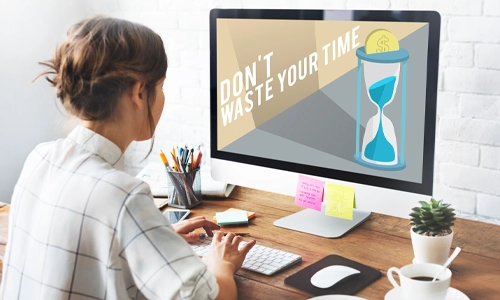 Woman working at a computer displaying a time management message and hourglass graphic