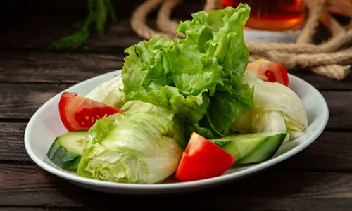 Plate with chopped tomato and cucumber and lettuce on the table