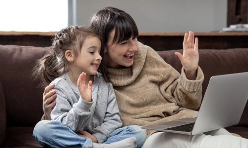 Mother and daughter smiling during a video call on a laptop