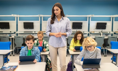 Teacher supervising students working on tablets in a classroom