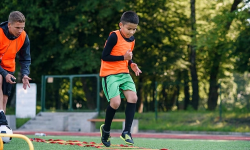 Young football player running through training obstacles during warm-up exercises