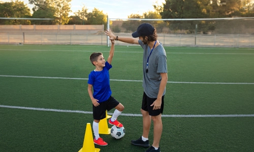 Football coach encouraging a young player during practice