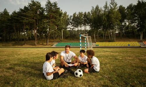 Group of children playing football under a coach's supervision