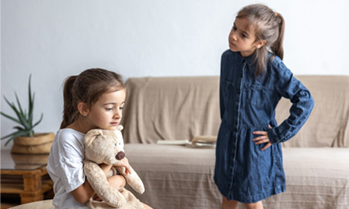 Two young siblings arguing and pulling on a toy in a living room.