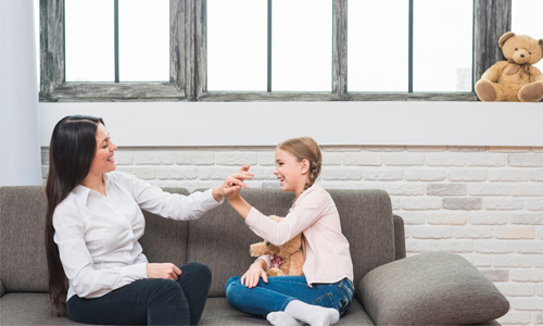 Image of a parent and daughter interacting warmly on a couch