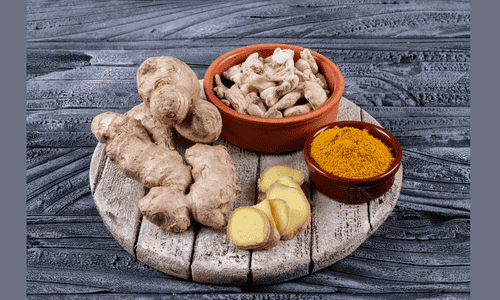 High angle view ginger in bowls with ginger slices and powder on wood