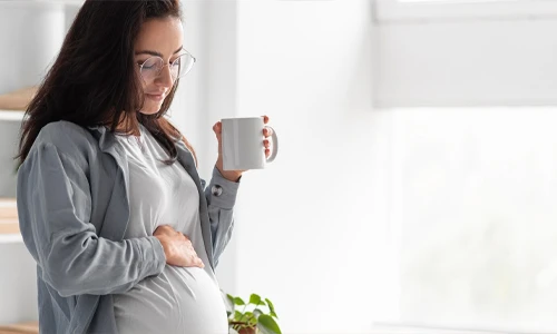 Pregnant woman at home holding a mug of coffee