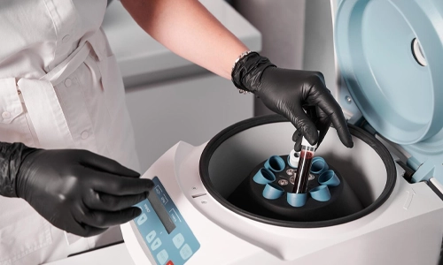 Researcher placing a test tube into a centrifuge