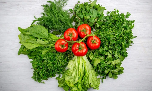 Top view of fresh leafy greens and tomatoes, representing a diet that supports uterine health.