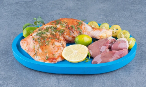Raw marinated chicken on a plate, representing the risks of undercooked foods during pregnancy.