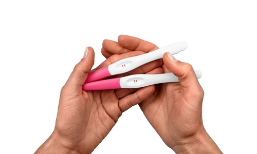 Close-up of a hand holding a positive home pregnancy test showing two lines for hCG detection.