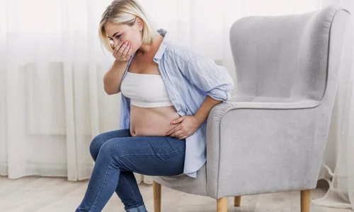 Stressed pregnant woman with her hand on her forehead due to severe pregnancy discomfort.