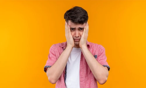 Sad young man with hands on his cheeks, representing male factor infertility and sperm health concerns.