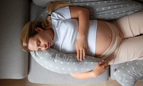 Top view of a pregnant woman using a nursing pillow for comfort while managing health conditions.