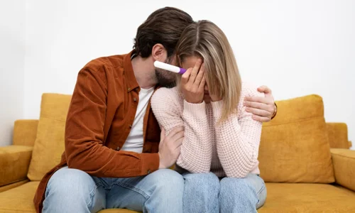 Medium shot of a couple looking at a pregnancy test, representing the emotional journey of early pregnancy loss and miscarriage.