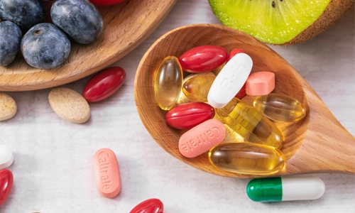 Fresh fruits next to medicine on a wooden spoon