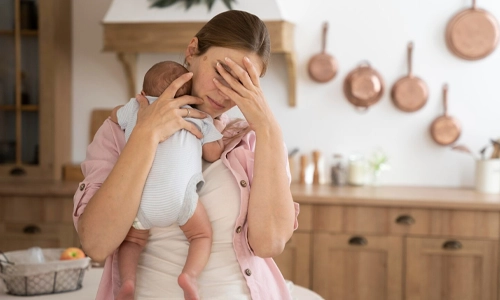 Mother holding her newborn baby during the postnatal recovery period in a hospital setting.