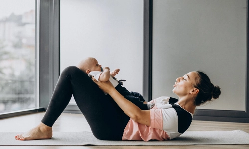 Mother practicing gentle yoga with her baby boy to aid in physical recovery and bonding.