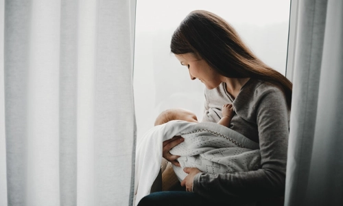 Mother holding and feeding her newborn boy, illustrating the physical and emotional bonding of the fourth trimester.