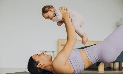 Mother and baby daughter practicing yoga at home to support gradual, healthy postpartum weight loss.