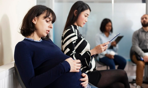 Pregnant woman rubbing her belly in a lobby, illustrating the need to recognize early complication signs.