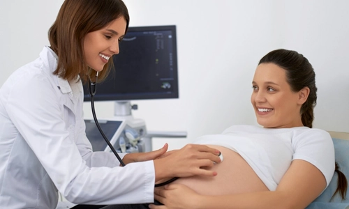 Doctor using a stethoscope to examine a pregnant woman, representing when to seek immediate medical attention.
