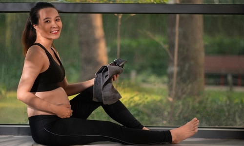 Young pregnant woman practicing a calm yoga pose at home for stress reduction.