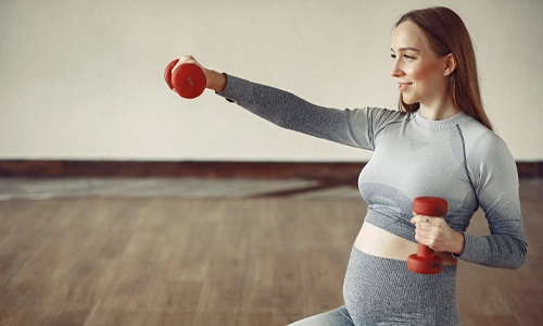 A Pregnant woman doing gentle exercise holding a dumbbell in hand.