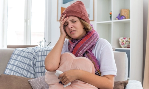 Unwell young woman holding a pillow and tissue, used to illustrate maternal health distress and preterm risks.
